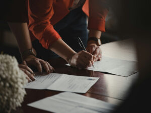 People bent over a desk writing or signing a document