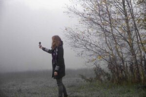 Woman holding up a compass in a cloudy landscape
