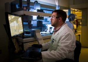 Man in lab coat sitting on chair in front of computer