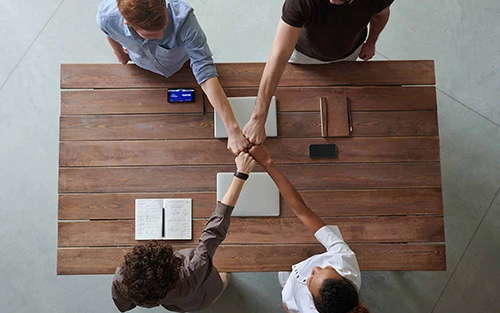 People fist bumping over a meeting table